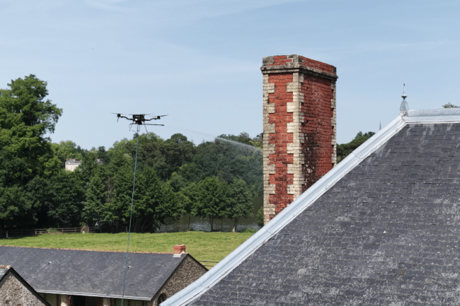 Drone en train de démoussage une toiture en tuiles